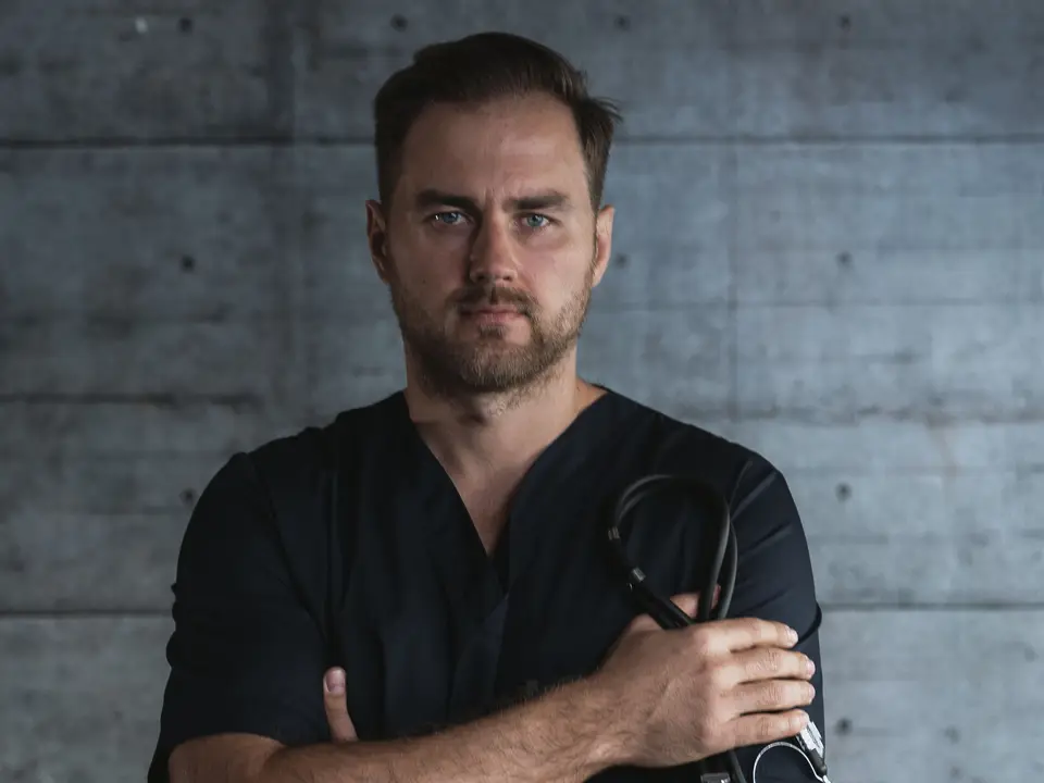 Stock photo: a doctor in dark scrubs holding a stethoscope
